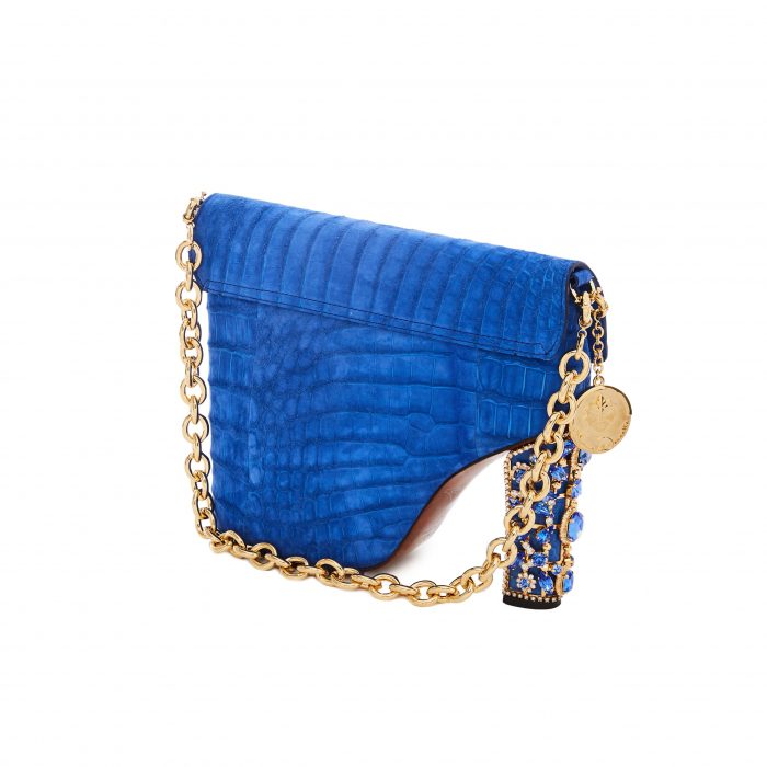 A blue purse with gold chain and a coin on it.