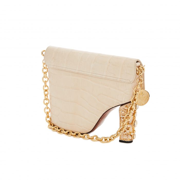A white purse with gold chain and a coin on the front.